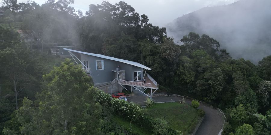 Angled view of a modern house overlooking a scenic coastal landscape with greenery Ibex Resorts, Coonoor (Tapas).