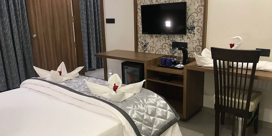 Suite with a bed, desk, chair and TV | Kyriad Hotel, Solapur