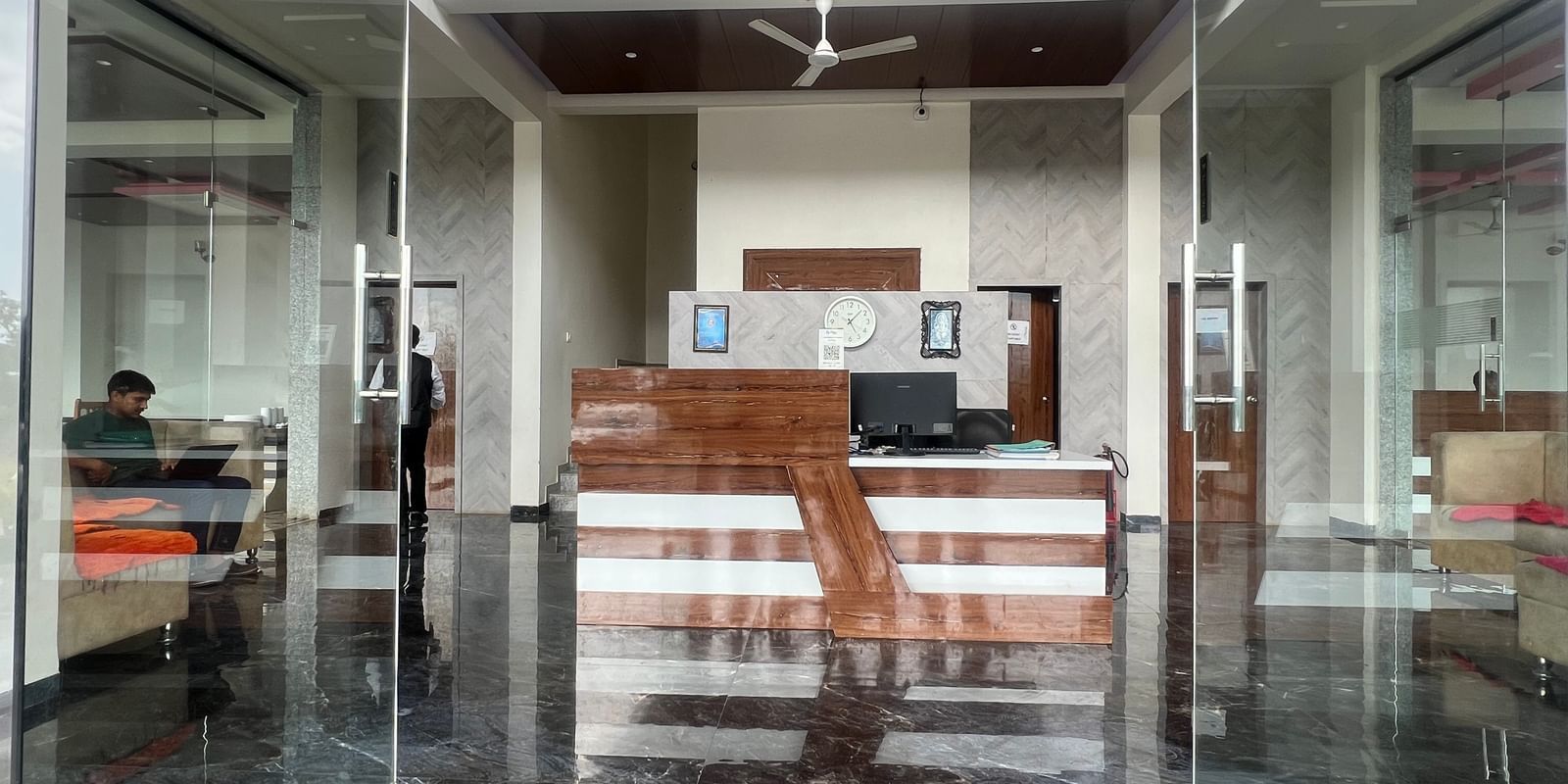Glass doors opening to the reception and lobby area of the 2-storey Daksh The Valley Resort, Saputara.