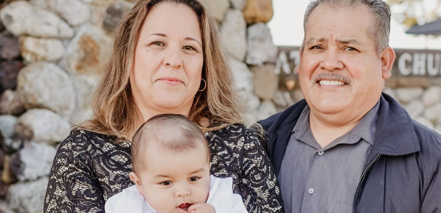 An image of a man and a woman who is holding a baby in her arms