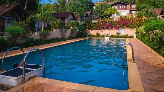 Resort pool with floral wall and villas at Stone Wood Resort, Mandrem