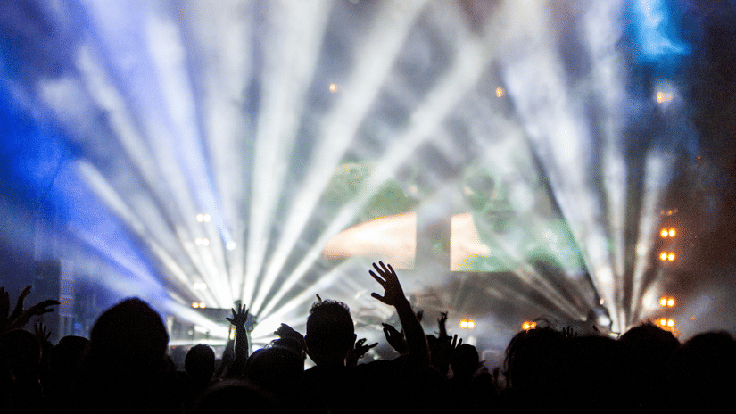 Crowd enjoying a live music performance with dramatic stage lighting, visual effects, and concert-style energy