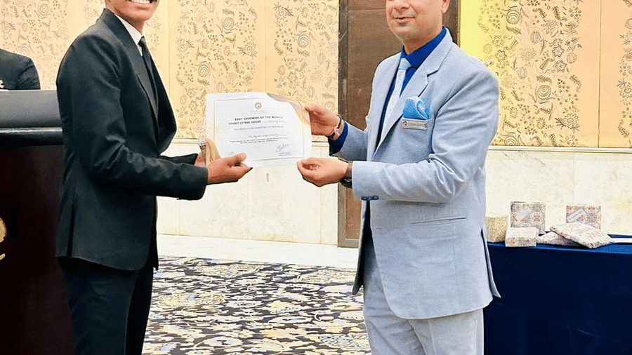 A person receives a certificate from another individual during a ceremony. They stand on a carpet.