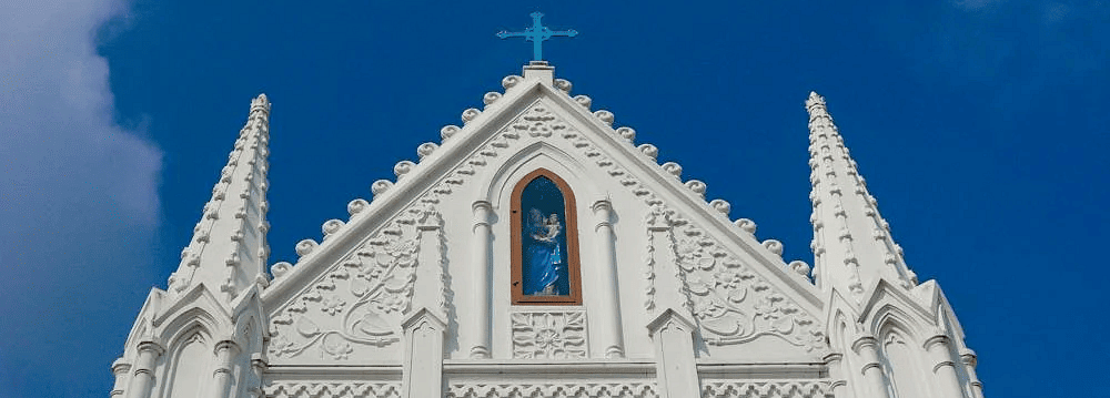 Facade of a church with wooden windows and a cross on top of the building.