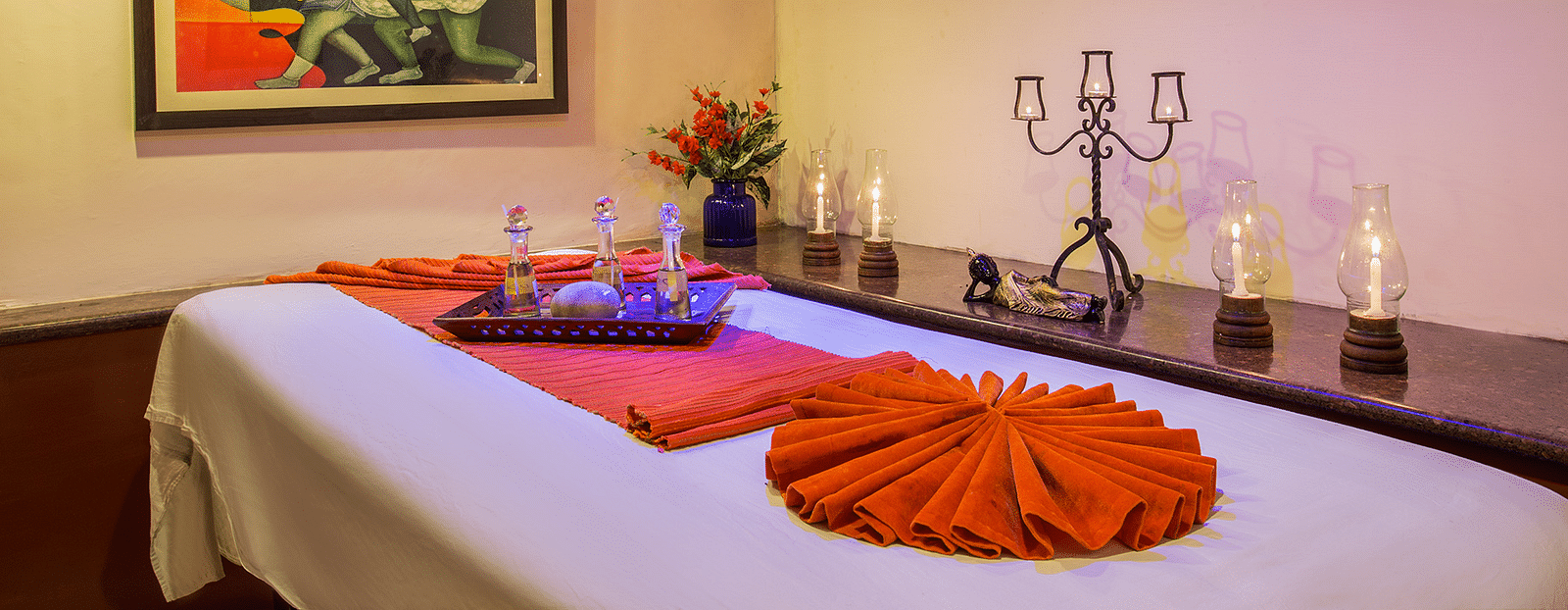 A spa table, candles beside it and a frame on the wall in a treatment room at our Spa in Nainital