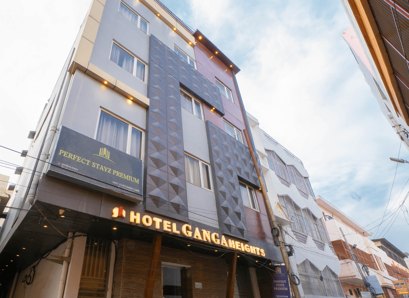 Exterior view of the multi-storey hotel building under a bright sky from a low angle - Perfectstayz Premium at Har Ki Pauri Road (Ganga Heights)