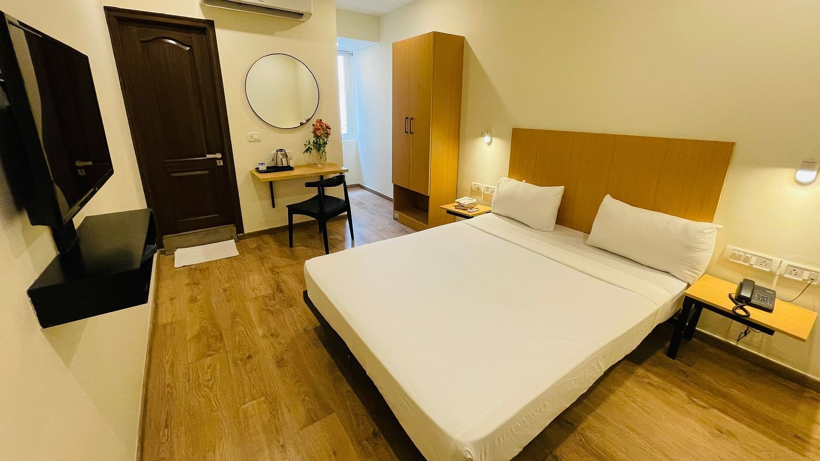 A double bed, a work desk, and a TV in a room at Sanctum Suites Richmond Road, Bangalore