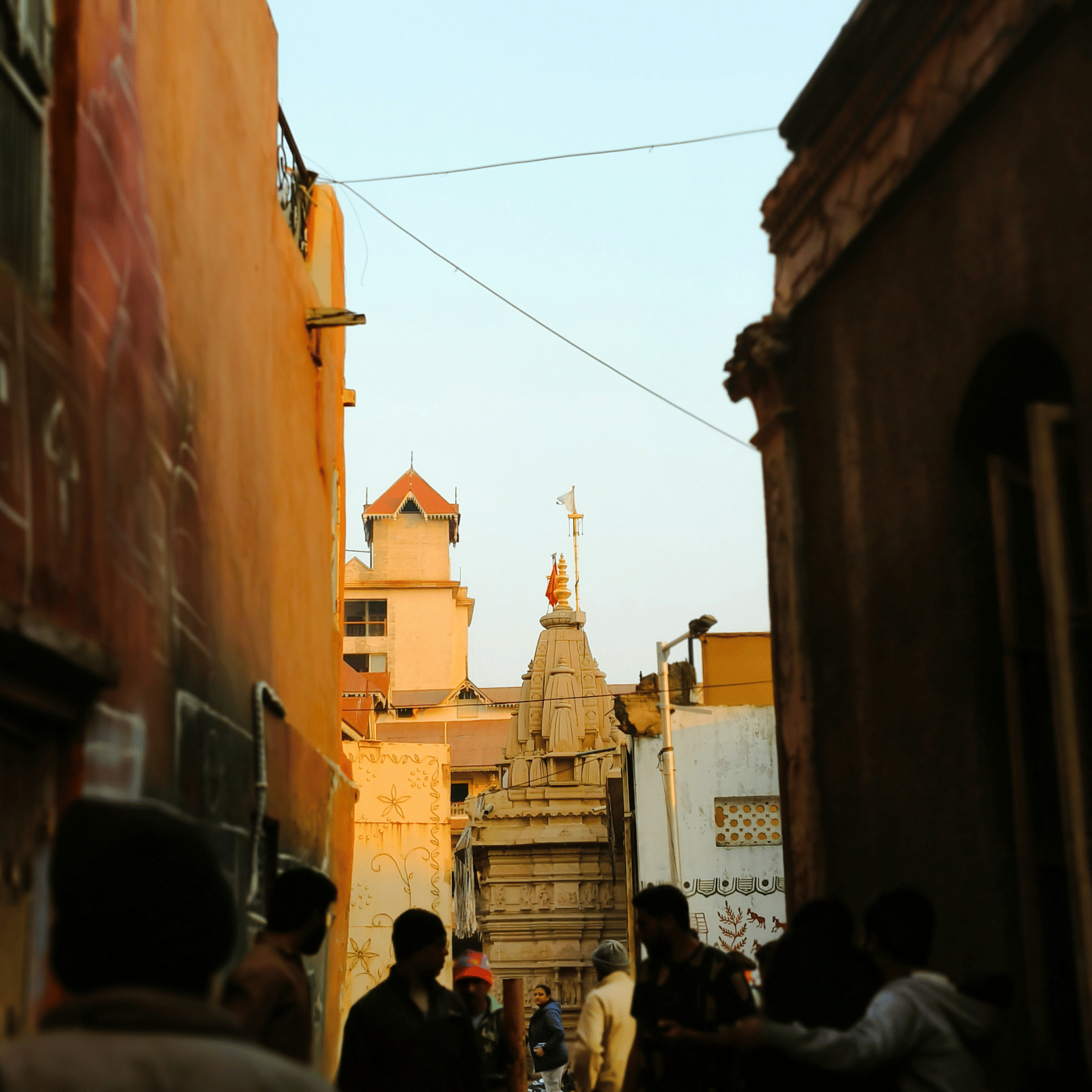 A dimly lit street with the silhouette of people walking in front.