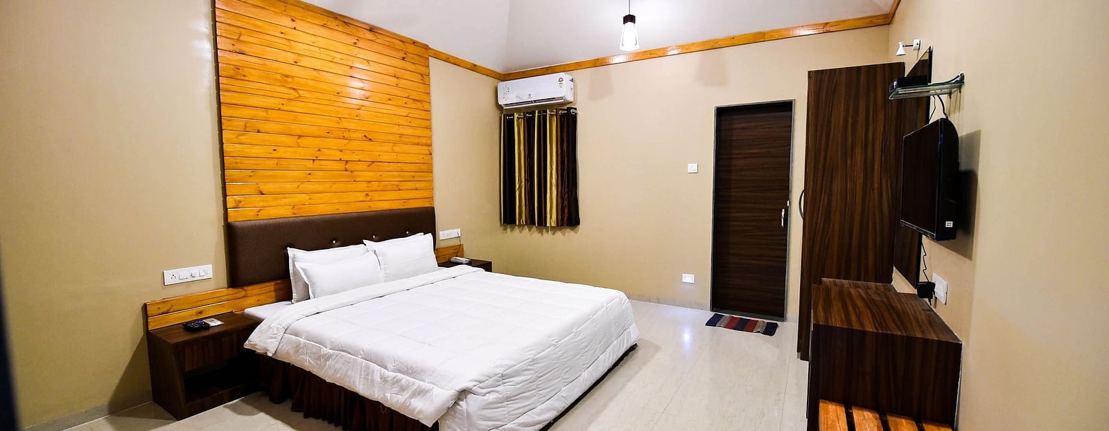 Overview of Deluxe Cottage at the Kanila Resort with a bed, bedside tables, wardrobe and a  ceiling fan.