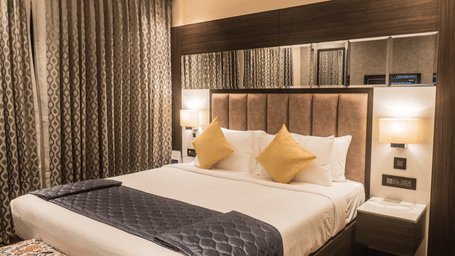 A Superior Room at Hotel Eastern Gate, Port Blair, featuring a bed, wooden flooring, and full length curtains.