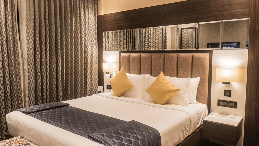 A Superior Room at Hotel Eastern Gate, Port Blair, featuring a bed, wooden flooring, and full length curtains.