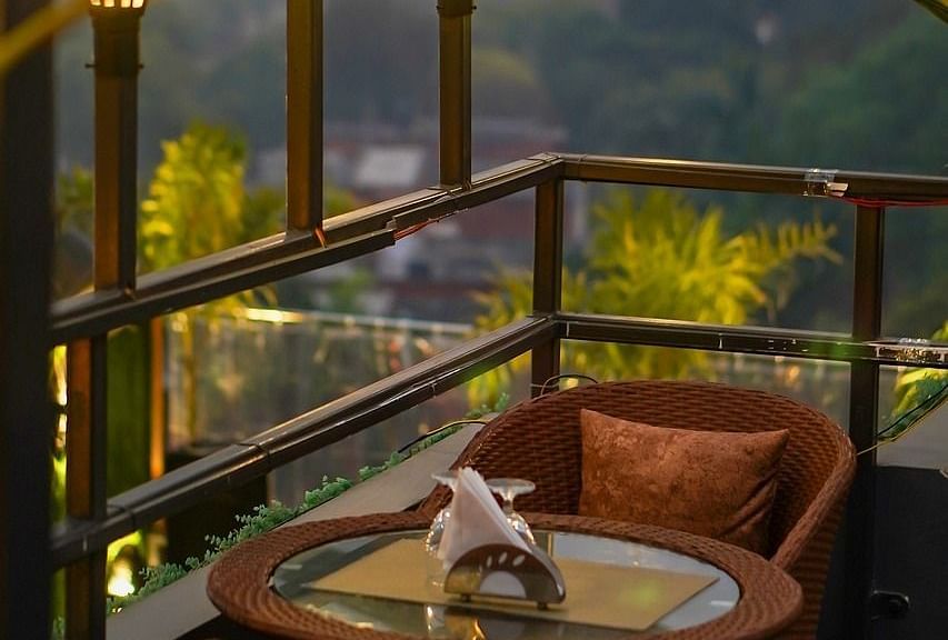 Two chairs facing each other on a terrace with warm lights besides it on a late evening.