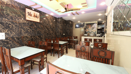 Restaurant at Perfectstayz Value Hills, Rishikesh featuring sets of table and chairs, and a kitchen counter with utensils.