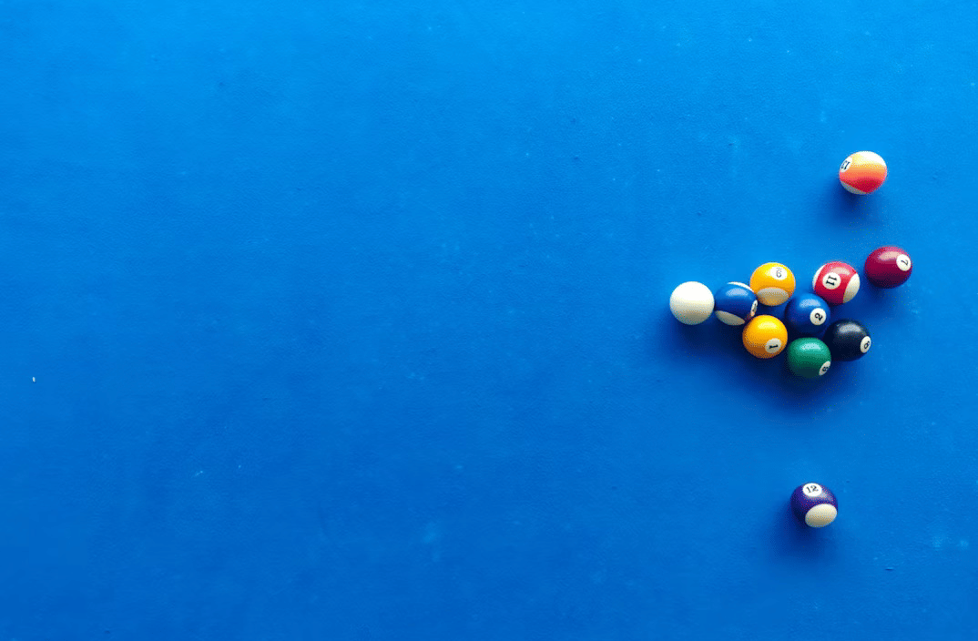 Billiard balls arranged for break on a pool table with ample space around them.