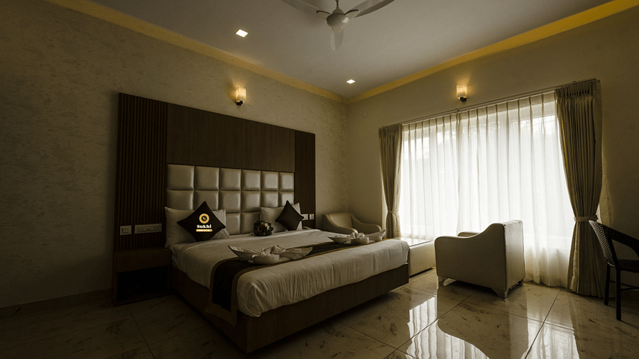 Suite featuring a king size bed, a chair, and sheer curtains. - Sukhi - A Luxury Stay Inn, Chikkamagaluru