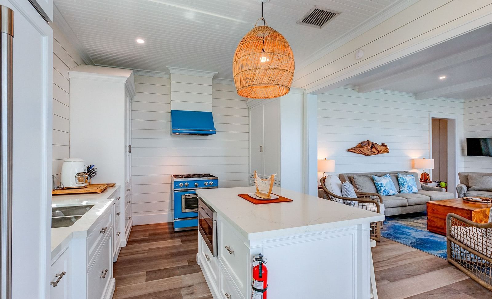 Open kitchen and living area with a white island, blue stove, and wooden accents | Abaco Inn