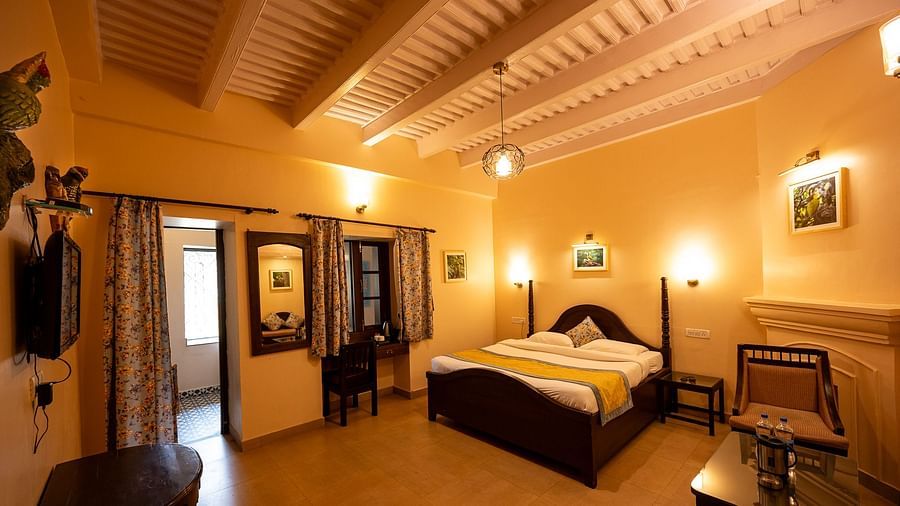  A warmly lit Oak Room with a four-poster bed, exposed wooden ceiling beams, and traditional furniture at The Pavilion, Nainital