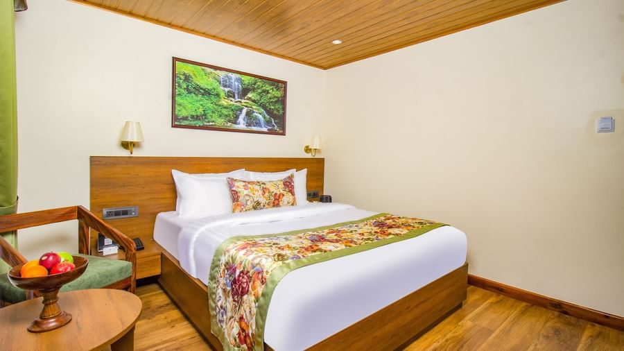 Elegant bedroom with king bed and wooden floor, table and wall decor at Mount Lungta Boutique Hotel and Spa.