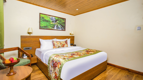 Elegant bedroom with king bed and wooden floor, table and wall decor at Mount Lungta Boutique Hotel and Spa.