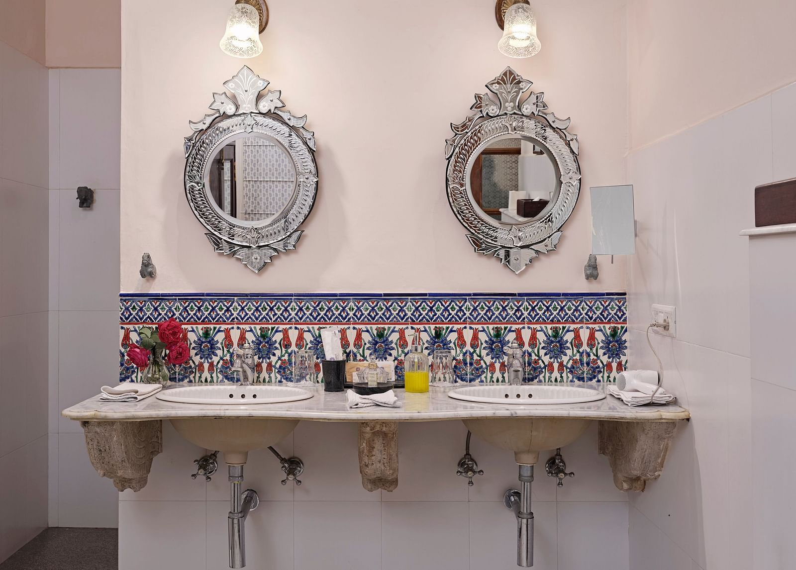 A bathroom with two ornate mirrors above twin sinks with colourful tiling - Dev Shree Deogarh