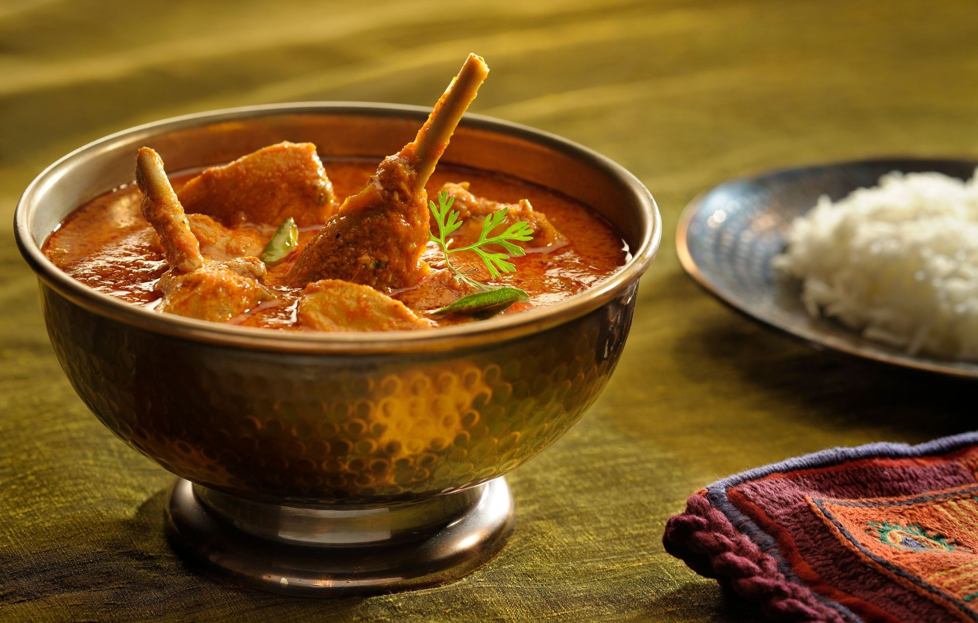 Natukodi Pulusu chicken curry in a brass bowl.
