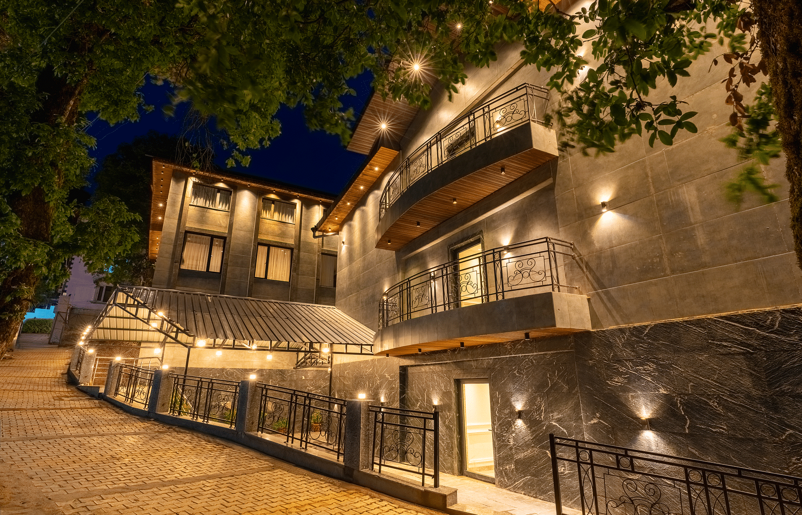An image of a well lit facade with trees around at Bedzzz Xclusiv Ikshana Luxe, Nainital