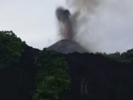 A thick plume of ash and smoke rising into the sky from the active volcanic crater peak on Barren Island.