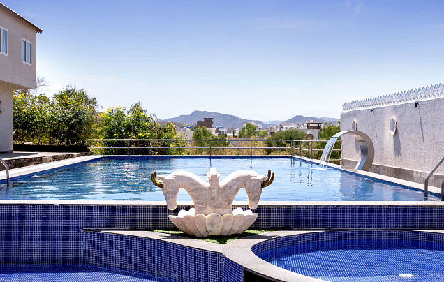 Swimming pool with sculpture under a clear sky. -  Bamboo Saa Resort & Spa, Udaipur