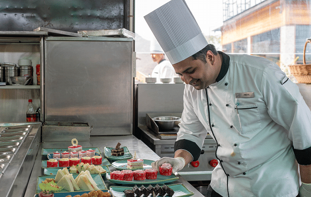 A chef smiling and looking at the food.