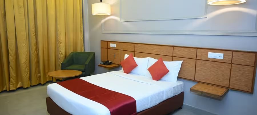 A well-designed hotel room with two beds, modern lighting, and a cosy seating area - Max Hotel Prayagraj.