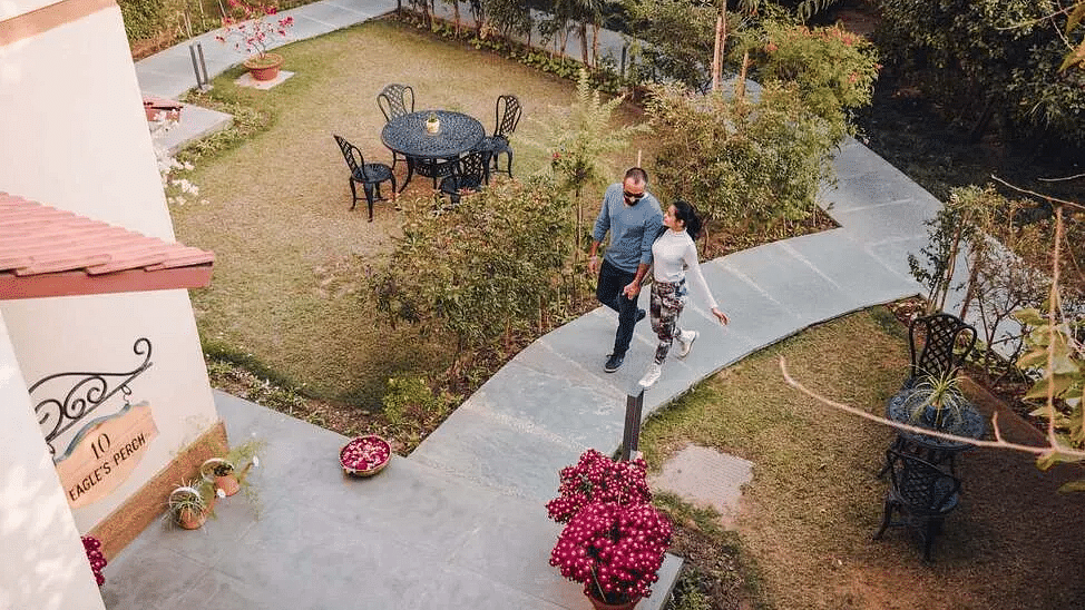 View from above of a garden area with seating and a person walking with a dog at Karma Chalets.