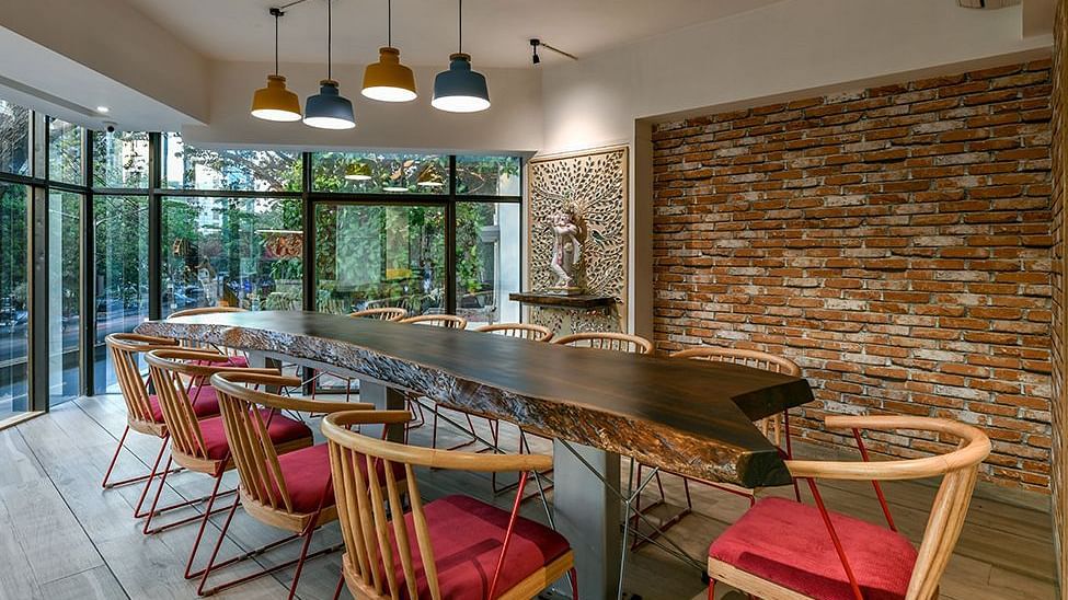 A seating area with a large wooden table, chairs around it, and warm lighting at Indie Stays