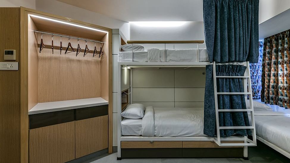  Bunk beds with curtains pulled to the side and a wooden cupboard with hangers available at Indie Stays
