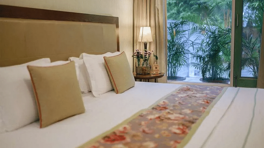Bedroom at Karma Chalets with a large bed, bedside lamps, pillows, and a window with trees visible outside.