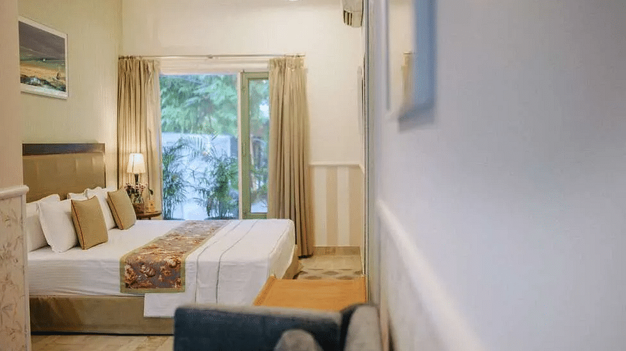 Bedroom at Karma Chalets with a double bed, side tables, wall art, and a window with views of outdoor greenery.