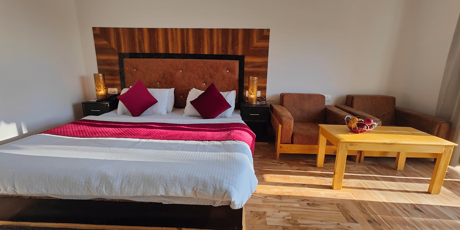 A wide-angle view of a bedroom with parquet flooring and a seating area at Indus Serenity Retreat.