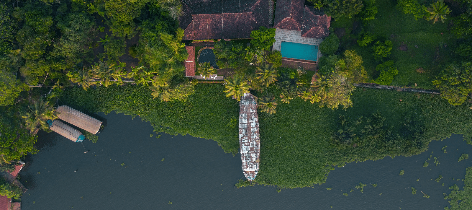 An aerial shot of BluSalzz Villas - Muhamma Resort, Alleppey surrounded by greenery and the Vembanad Lake