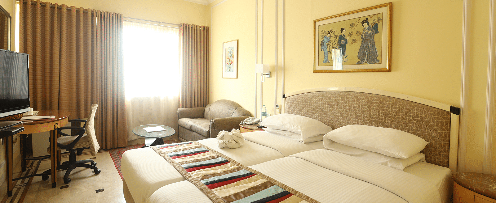 Twin beds in the Superior Room with sunlight peeking through the windows at Regency Hotel, Mumbai.
