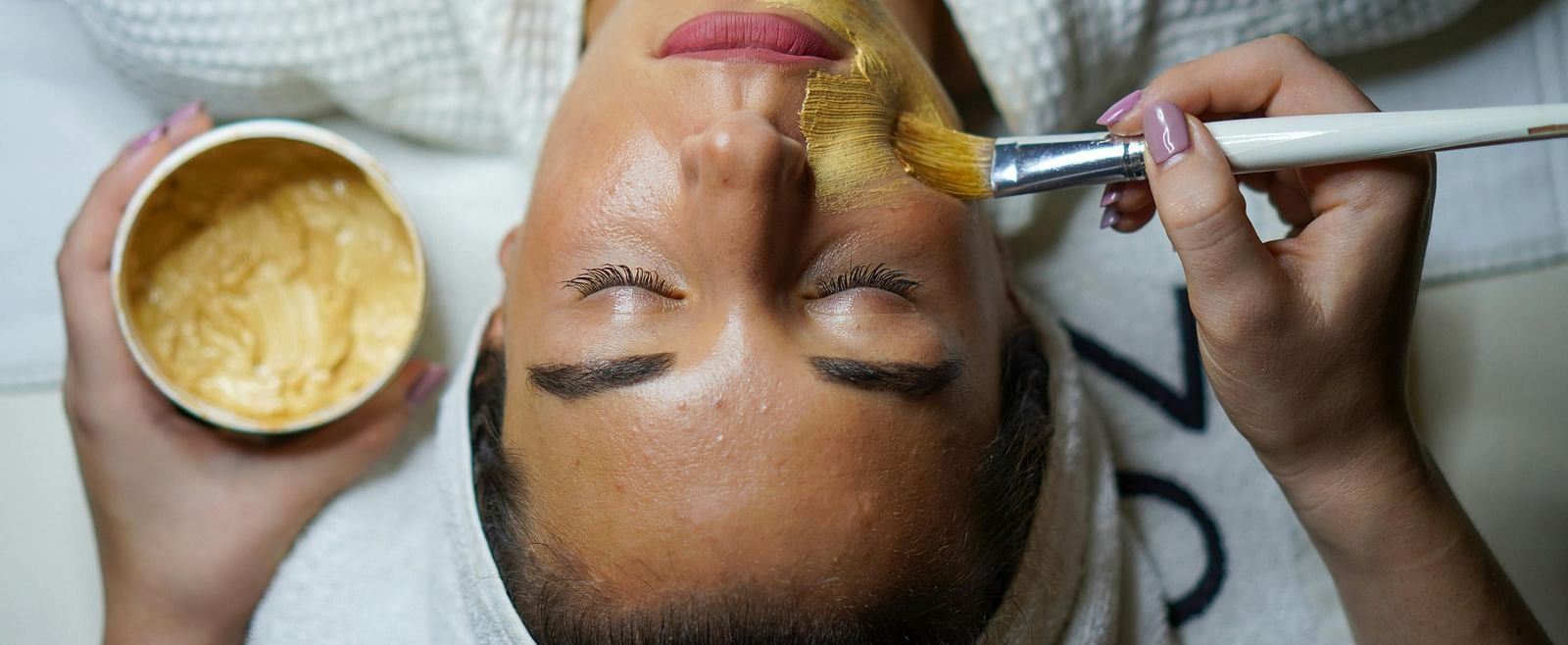 A top angle shot of a lady applying face mask.
