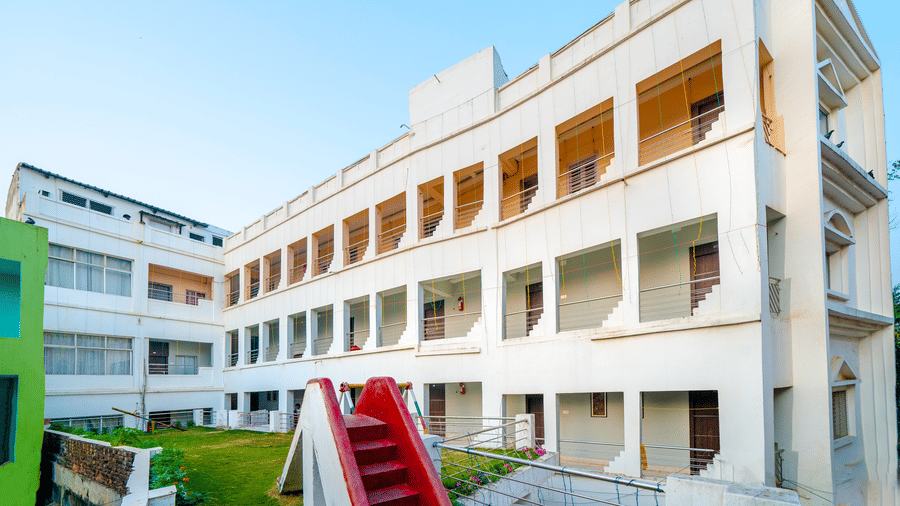 A wide exterior view of the multi-storey, white hotel building with rows of windows and balconies under a clear blue sky - Hotel Dolphin Puri