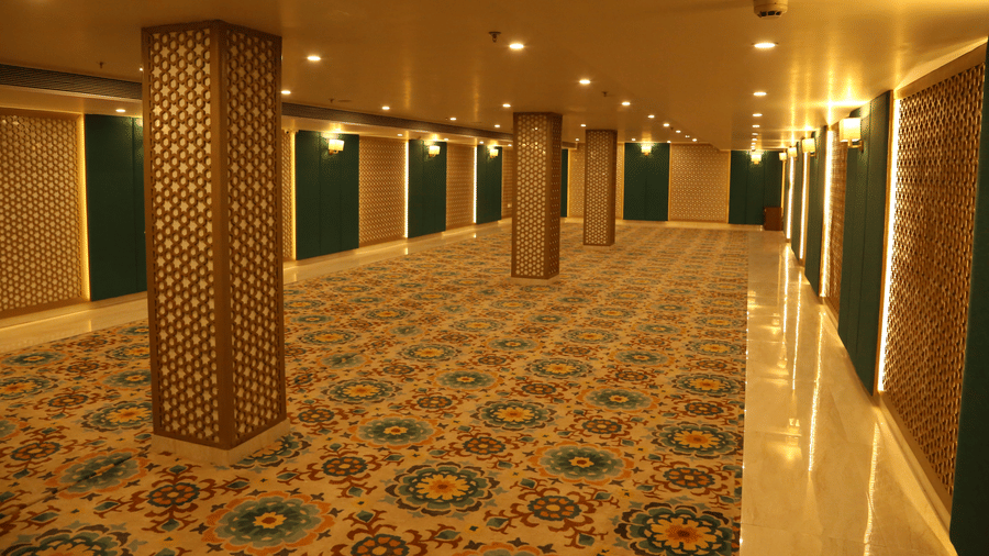 Indoor hallway at Comfort Inn Sapphire by Eastlynn Collections, Jaipur, featuring a patterned carpet, columns with latticework, and warm wall lighting.