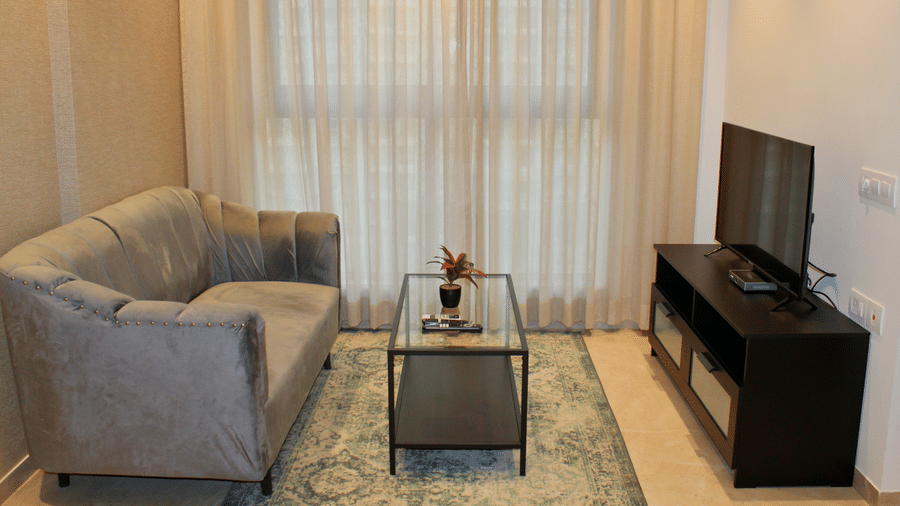 Side view of living area with sofa coffee table and a TV set - Maxxvalue Apartment, Hiranandani, Powai