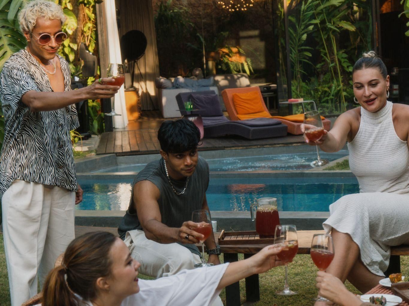 A picture of a few people having drinks next to a swimming pool