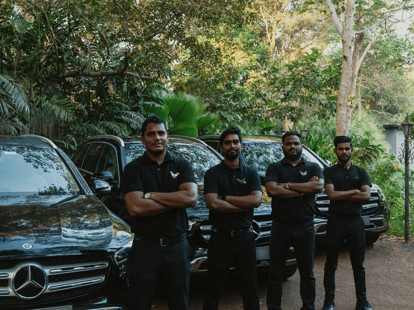 Picture of four men standing in front of a few cars parked