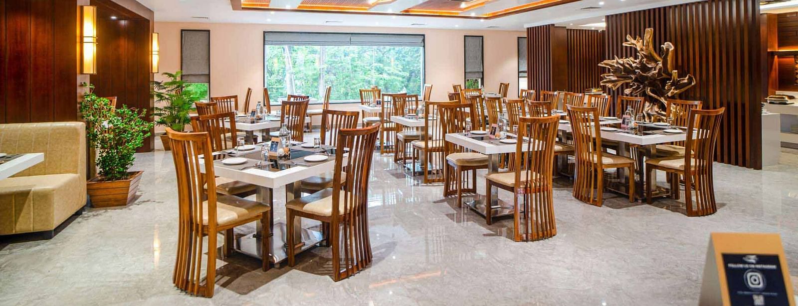 The warmly lit dining area of Pakeezah Restaurant at Mansha Palace features neatly set tables and comfortable wooden chairs.