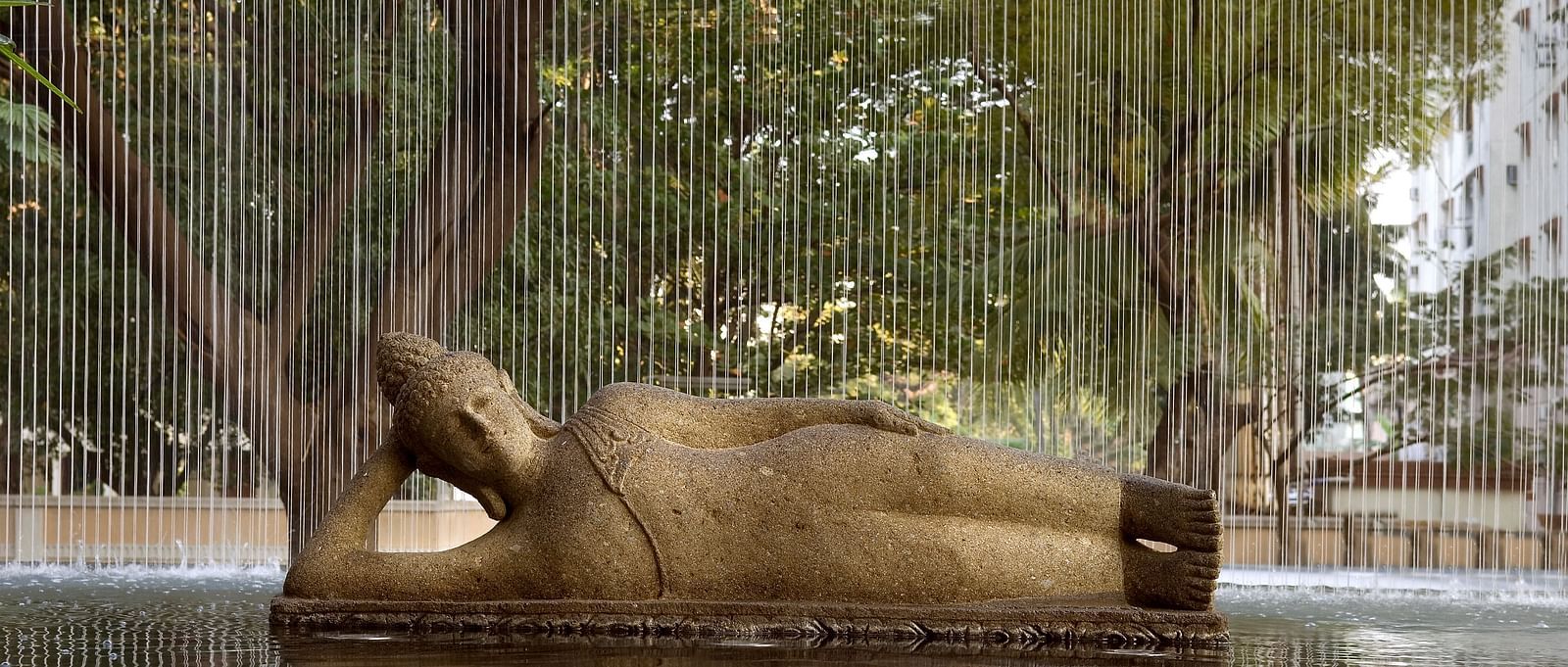 Bronze sculpture of a reclining figure with a water falling in front, creating a unique visual effect - The Raintree, St. Mary's Road.