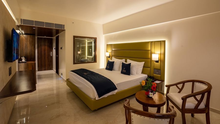 Side view of Deluxe King with plush bed and bedside tables seating area TV set coffee and tea maker and partial view of the washroom - Mastiff Grand - The Sia Palace Suites Banquets Khopoli