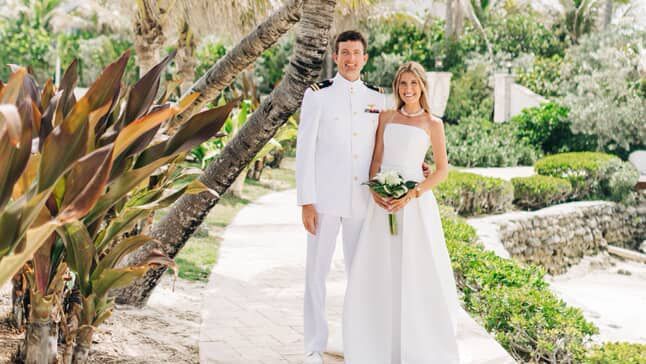 Two people in wedding attire standing among palm trees, Abaco Inn grounds.