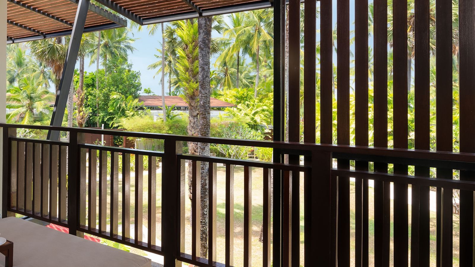 Balcony view with wooden screen and outdoor seating at Ramada Resort by Wyndham Khao Lak.