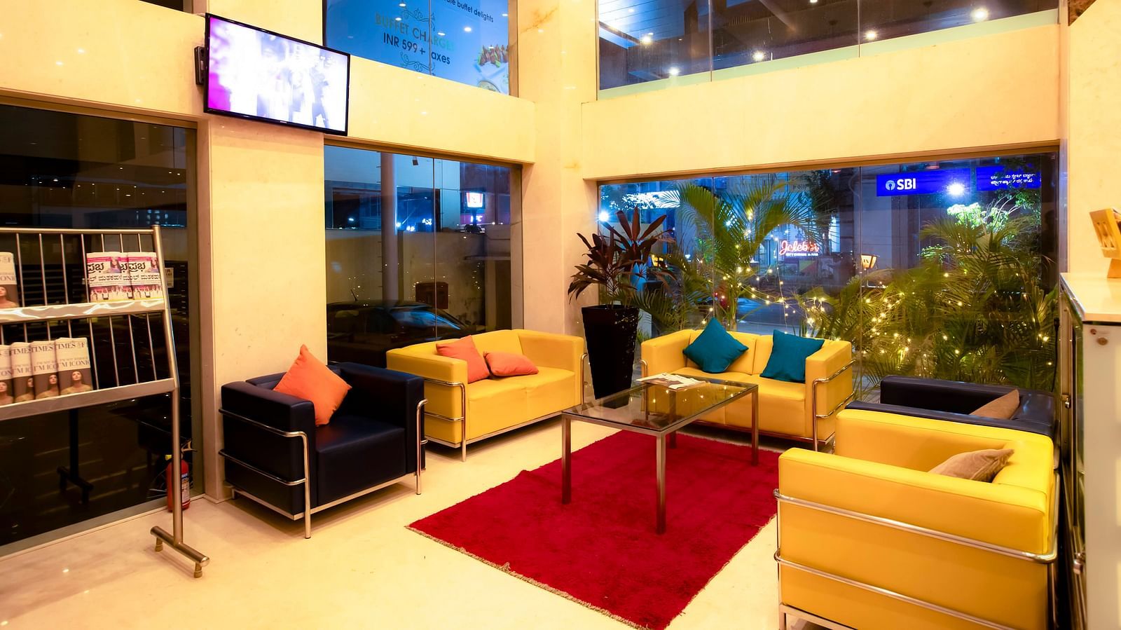 Lobby of The Cunningham Hotel featuring newspapers stacked in the rack next to the sitting area with vibrant couches placed around a centre table
